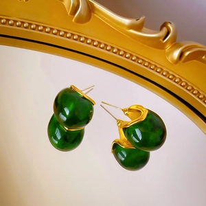 Vue détaillée de boucles d'oreilles en résine ambre reflétées sur un miroir doré