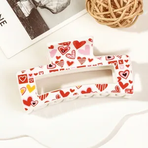 Detail of white rectangular hair claw clip with colorful heart pattern on a decorative tray