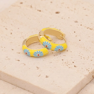 Gros plan de boucles d'oreilles créoles marguerites jaunes sur pierre texturée