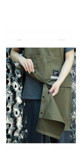 Detail view of olive green work apron featuring removable hem and durable canvas fabric