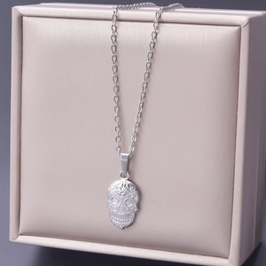 Close-up of a silver skull pendant with rose details on a stainless steel chain