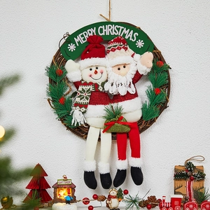 Christmas wreath with Santa and Snowman plush dolls on a textured white wall