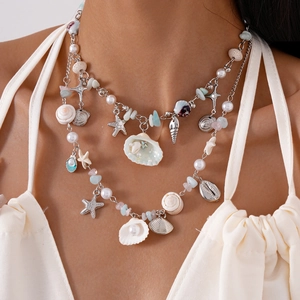 Detail of beach style multilayer necklace with shell starfish and pearl charms for women