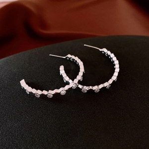 Vue macro de boucles d'oreilles argentées en C avec hexagones et incrustations de zircon