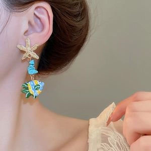 Detail of starfish earring with turquoise stones and colorful fish pendant on model