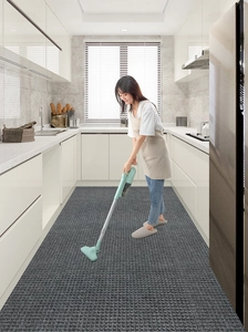 Deep gray textured rubber floor mat being cleaned with a cordless vacuum in a kitchen