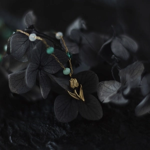 Macro detail of tulip flower pendant on vintage gold necklace with green beads