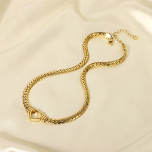 Detail of 14K gold plated hollow heart pendant on a flat Cuban chain over silk fabric