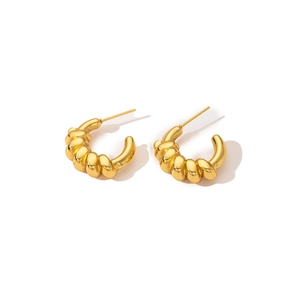 Macro shot of gold croissant style twisted C-shape hoop earrings with a glossy finish