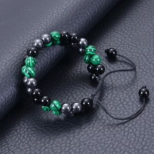 Detail of double-layer woven malachite and obsidian beaded bracelet on black texture