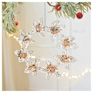 Macro shot of acrylic snowflake wreath with gold sequins hanging on a pine branch