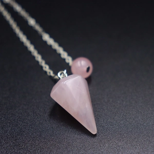 Detailansicht eines sechseckigen Rosenquarz-Pendels mit feiner silberfarbener Kette