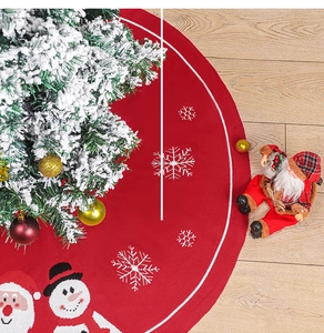 Gros plan sur la jupe de sapin de Noël tricotée rouge avec motifs bonhomme de neige et Père Noël