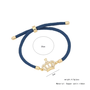 Dettaglio del bracciale in nastro di raso blu con ciondolo a corona dorata e cristalli