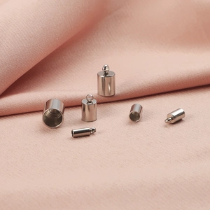 Polished silver metal cylinder end caps for DIY jewelry making on pink fabric