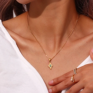 Détail du collier doré avec pendentif étoile et une pierre œil-de-chat verte ovale