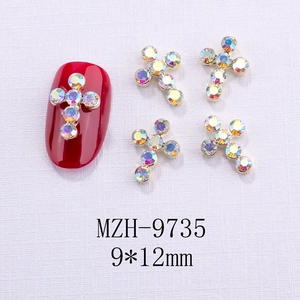 Dettaglio del charm per unghie a croce dorata 9x12mm con strass AB su manicure rossa