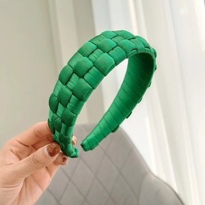 Detailed view of handmade green woven fabric headband with smooth satin texture