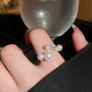 Close-up of a gold pearl ring with a central gemstone worn on a finger for a chic look