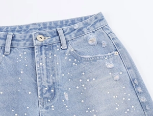 Vue détaillée du short en jean avec perles blanches et détails usés à effet déchiré