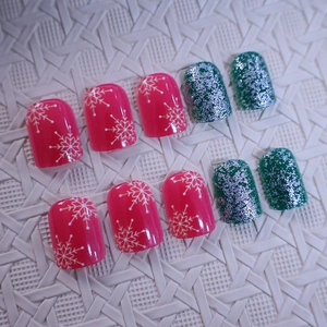 Short Christmas press-on nails with red snowflake patterns and green glitter finish