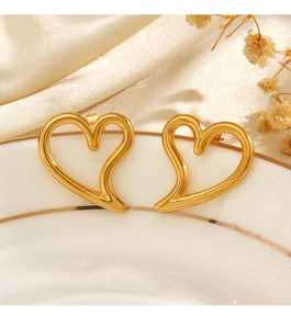 Detail of hollow heart stud earrings in gold finish on a decorative white display plate