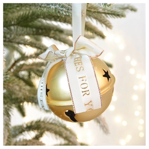Close-up of golden Christmas bell with a white ribbon and warm bokeh lights decoration