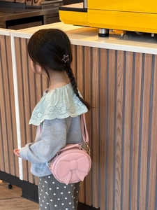 Detail of pink round kids crossbody bag with 3D bow and adjustable strap in a cozy setting