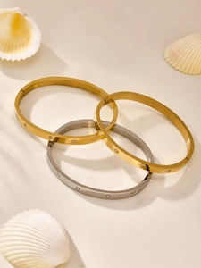 Detail view of stacked gold and silver bangles with star motifs and zircon accents