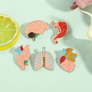 Five-piece set of creative organ enamel pins including brain, heart, and lungs on green background