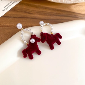 Macro detail of wine red flocked pony and pearl earrings on a white jewelry tray