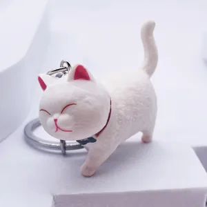 Detailed view of white cartoon cat keychain with blue bow and silver metal keyring
