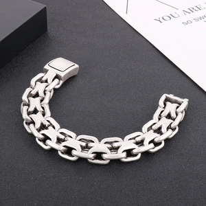 Detailed close-up of a silver stainless steel curb chain bracelet on a black texture