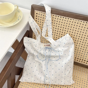 Detail of canvas tote bag featuring blue heart prints and light blue drawstring tie