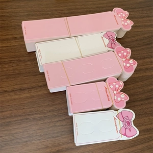 Pink and beige long hair clip display cards with bow design on a wooden table