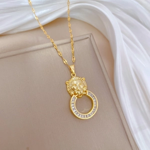 Detailed close-up of golden lion head pendant with zircon ring on silk background