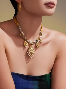 Dettaglio della collana con ciondolo a cuore dorato, nastro di seta e orecchini abbinati