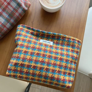 Detail of colorful plaid tweed cosmetic bag with Simple Wish label on wooden table