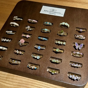 Macro view of assorted enamel butterfly and floral rings displayed on a wooden tray