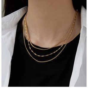 Detailed close-up of a three-layer gold titanium steel chain necklace on a model