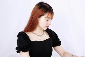 Dettaglio della collana a catena d'argento con pendente rettangolare indossata da una modella