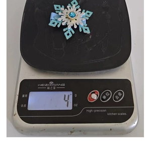 Macro detail of 4g snowflake rhinestone hair clip on an electronic scale for weight check