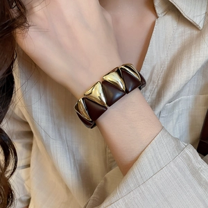 Detail of a vintage geometric wide cuff bracelet with dark brown and gold triangle links