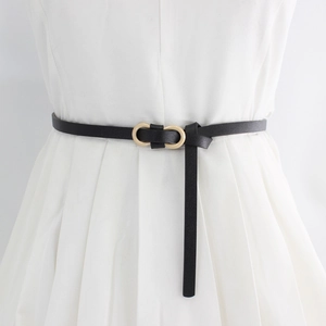 Minimalist black leather skinny belt with golden oval double ring buckle on white dress