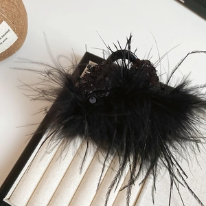 Macro detail of elegant black feather hair claw clip with sequins on silk fabric