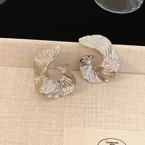 Detailed macro view of silver studs with abstract spiral texture on a beige jewelry display