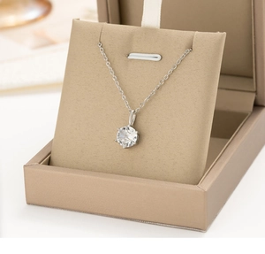 Macro shot of silver six-prong necklace with round zircon in a beige jewelry box