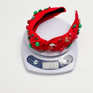 Red Christmas rhinestone knotted headband shown on a digital scale weighing 69.3 grams