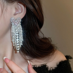 Macro detail of long tassel earrings with sparkling pink heart zircons and silver finish