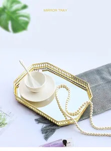Macro detail of octagonal gold metal mirror tray with hollow wire frame and jewelry